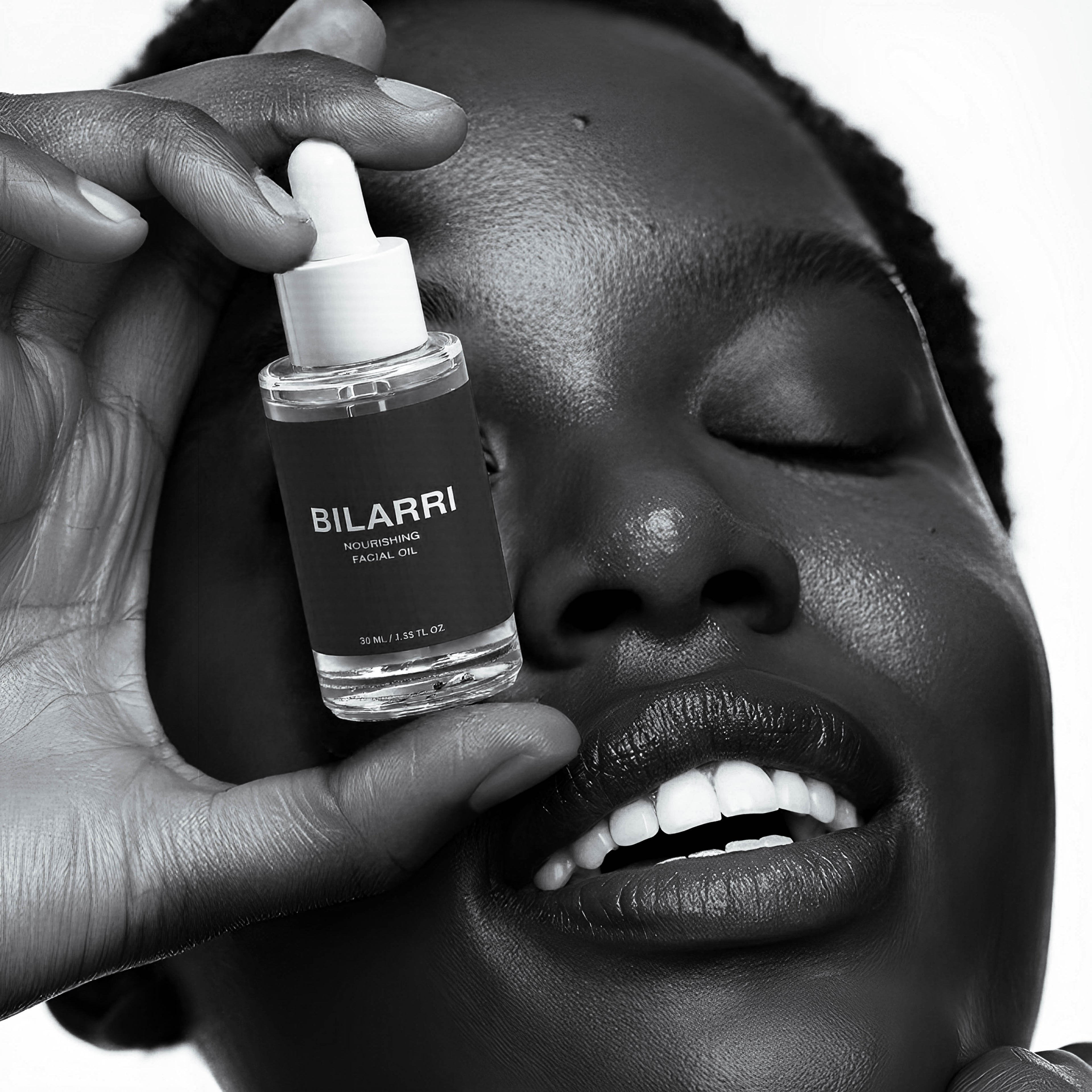 Person holding a Bilarri skincare dropper bottle close to their face