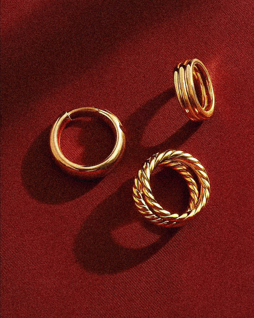 Three gold hoop earrings on a red background