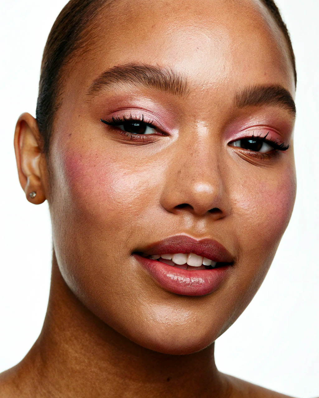 Close-up of a person with pink eyeshadow and lipstick on a white background