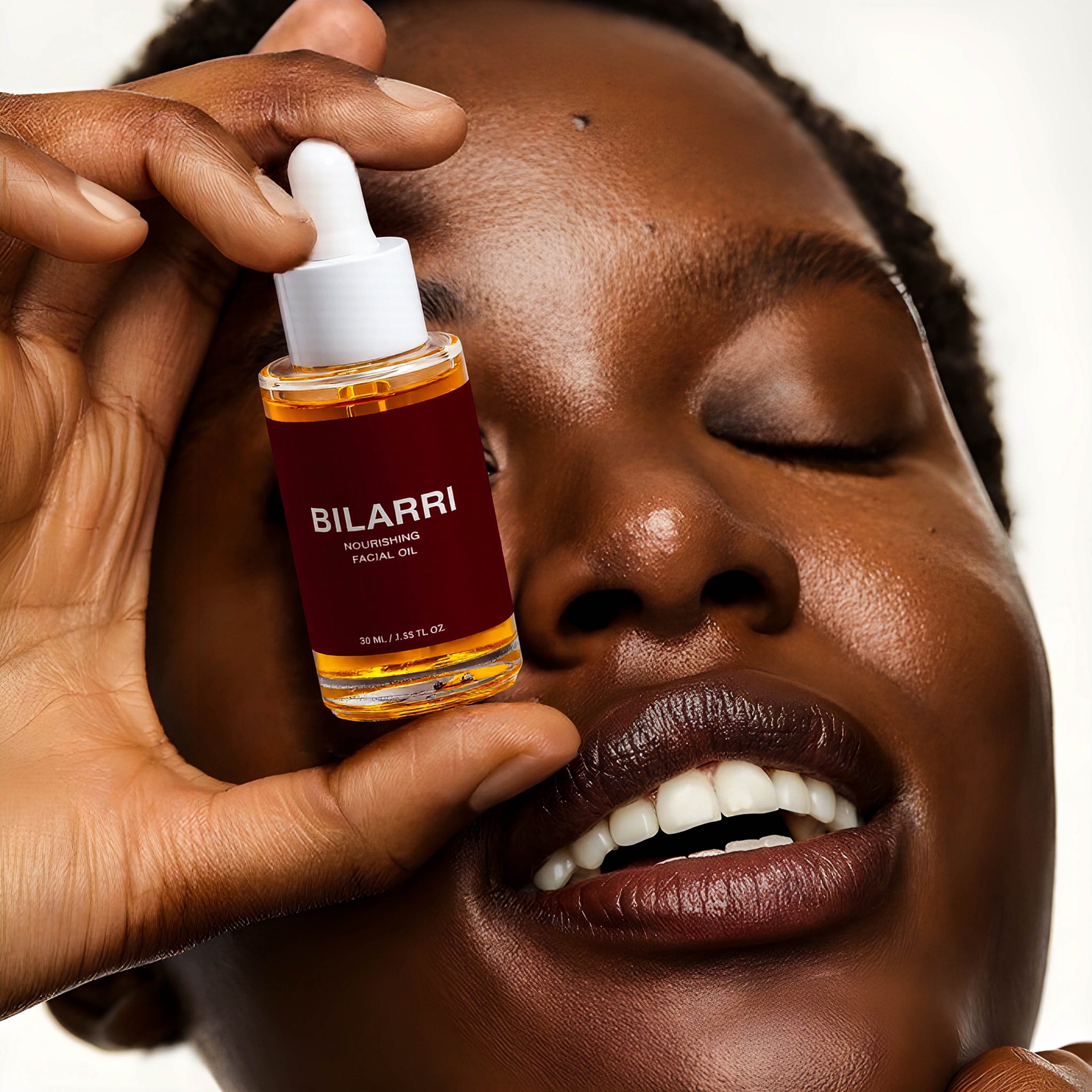 Person holding a bottle of Bilarri facial oil close to their face.