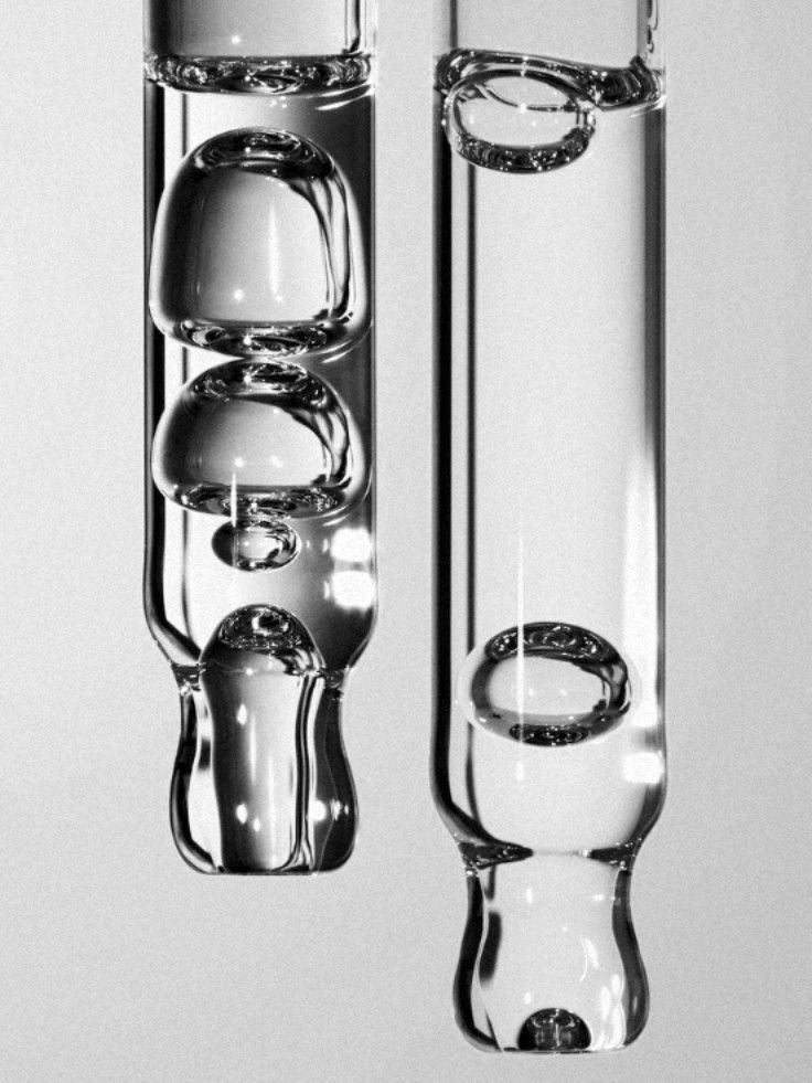 Two glass tubes with water droplets on a gray background