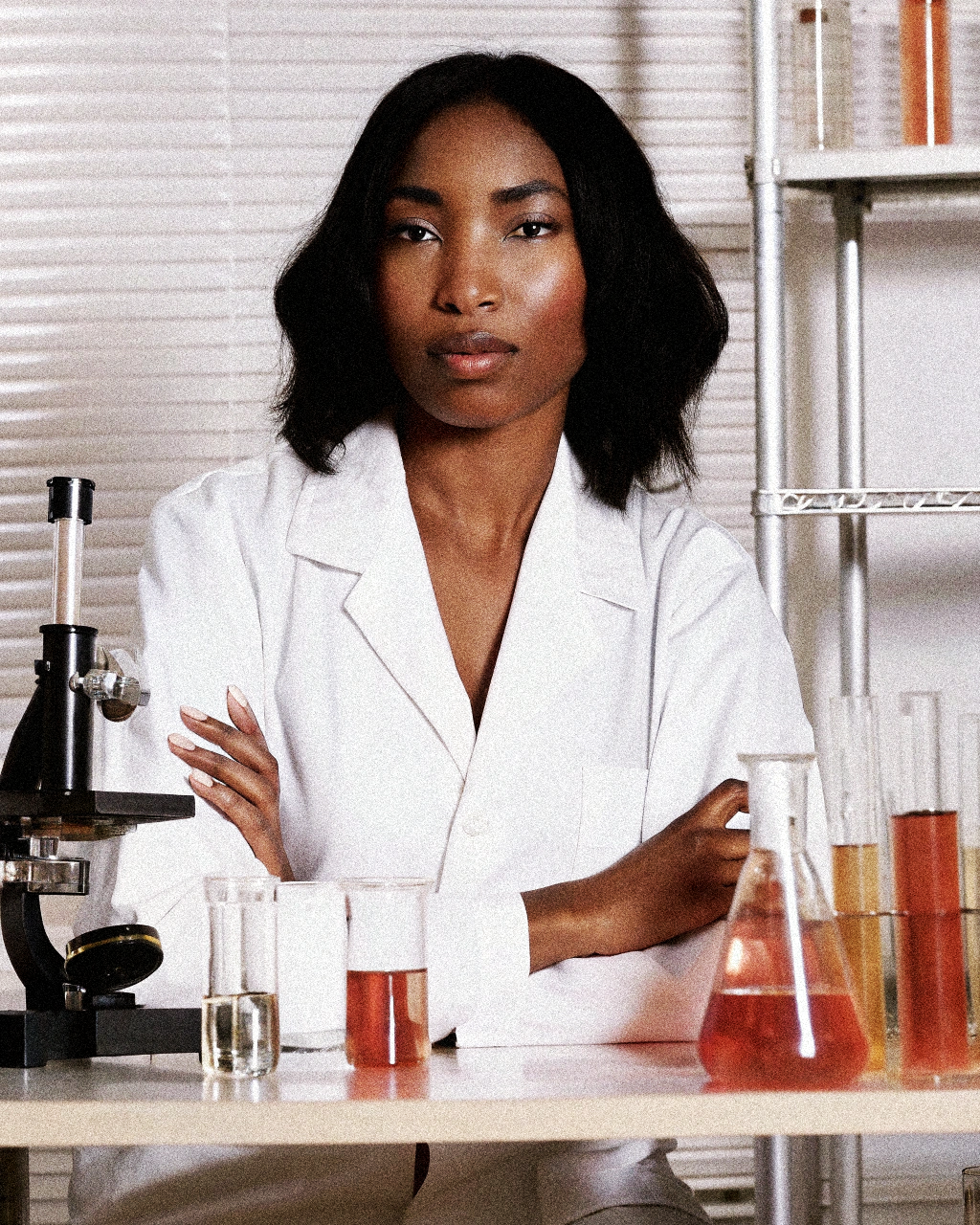 Person in a lab coat standing in a laboratory setting with scientific equipment.